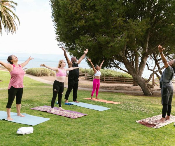 Three women practicing a group yoga pose outdoors.